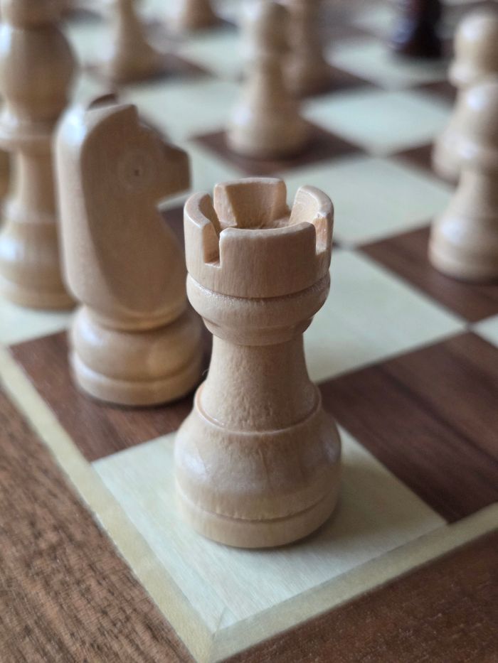 Close-up of a wooden rook and knight on a chessboard, highlighting strategic play.