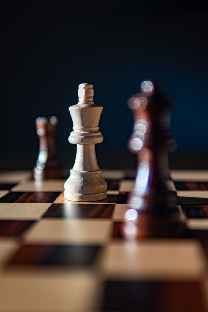 Artistic close-up of a chessboard featuring the king and other pieces in dramatic lighting.